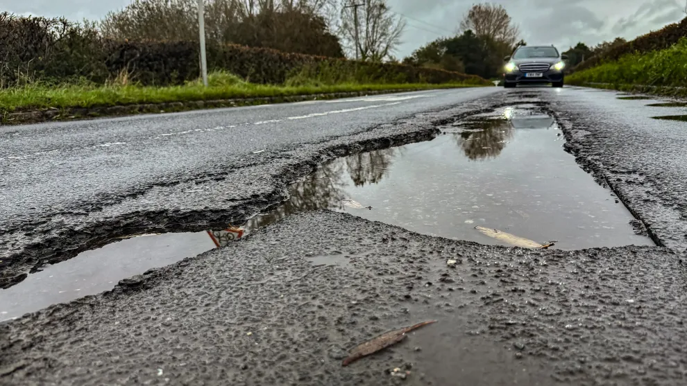 Close-up of a deep pothole in a tarmac road caused by repeated freeze–thaw cycles