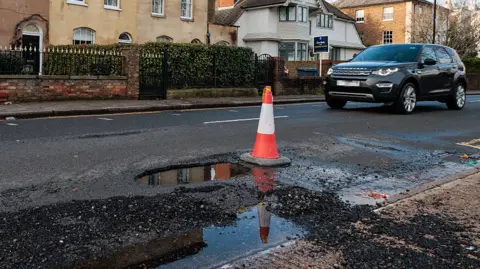 Large pothole on a busy A-road near Newark posing a risk to vehicles after winter weather